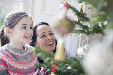 Glückliche Mutter und Tochter beim Schmücken des Weihnachtsbaums - HOXF03791