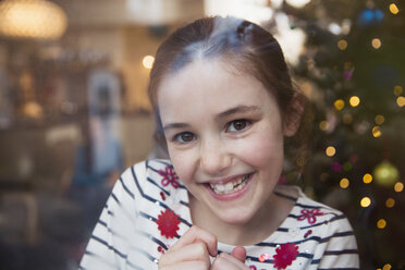 Porträt lächelndes, selbstbewusstes Mädchen im Weihnachtswohnzimmer - HOXF03792