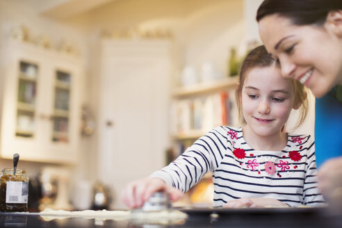 Mutter und Tochter beim Backen, mit Ausstechformen in der Küche - HOXF03796