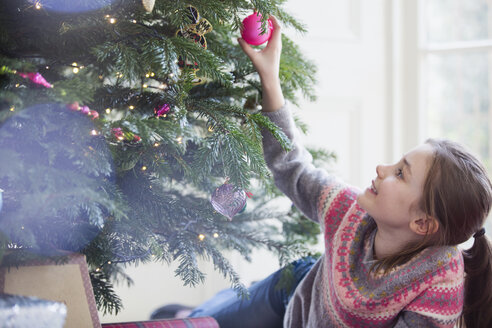 Neugieriges Mädchen berührt das Ornament am Weihnachtsbaum - HOXF03807