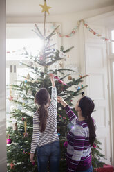 Mutter und Tochter schmücken den Weihnachtsbaum - HOXF03809