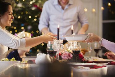 Familie reicht Essen weiter und genießt das Weihnachtsessen bei Kerzenschein - HOXF03815