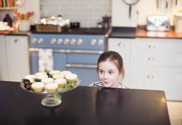 Cute girl eyeing Christmas pies on kitchen counter - HOXF03817