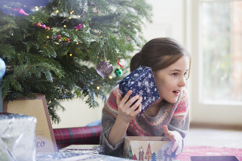 Neugieriges Mädchen schüttelt Weihnachtsgeschenk - HOXF03819