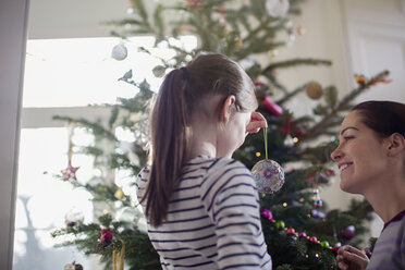 Mutter und Tochter schmücken den Weihnachtsbaum - HOXF03822