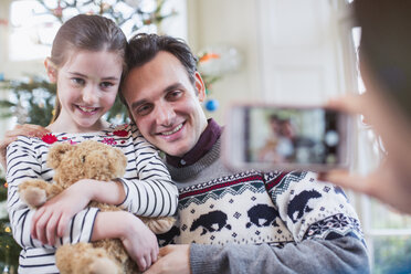 Vater und Tochter posieren für ein Foto im Weihnachtswohnzimmer - HOXF03824