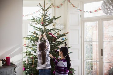 Mutter und Tochter schmücken den Weihnachtsbaum - HOXF03839