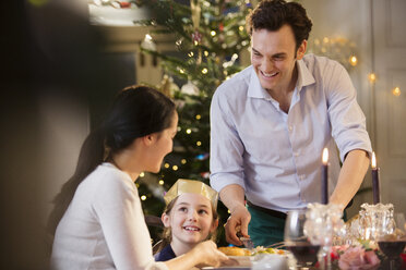 Glückliche Familie beim Weihnachtsessen bei Kerzenschein - HOXF03844
