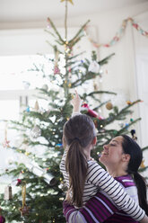 Liebevolle Mutter und Tochter mit Blick auf den Weihnachtsbaum - HOXF03846