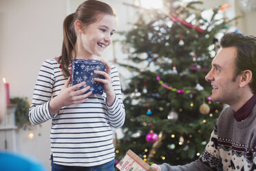 Father and daughter with gifts in front of Christmas tree - HOXF03853