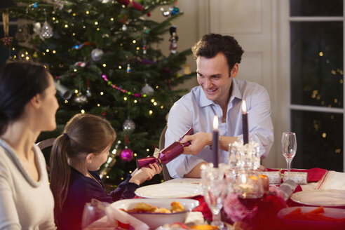 Vater und Tochter ziehen bei Kerzenlicht am Tisch Weihnachtsgebäck - HOXF03863