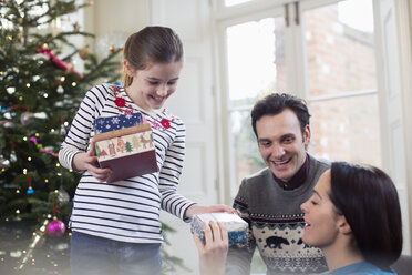 Familie öffnet Weihnachtsgeschenke im Wohnzimmer - HOXF03875