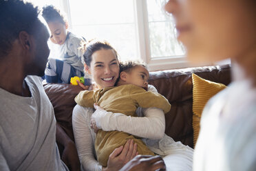 Glückliche Mutter kuschelt mit ihrem kleinen Sohn und entspannt sich mit ihrer Familie auf dem Wohnzimmersofa - HOXF03892