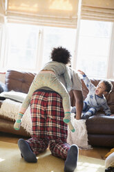 Vater und Kinder im Pyjama spielen im Wohnzimmer - HOXF03899