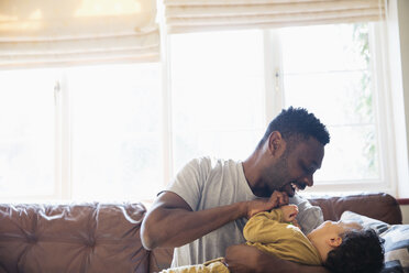 Verspielter, anhänglicher Vater und Sohn kuscheln auf dem Wohnzimmersofa - HOXF03903