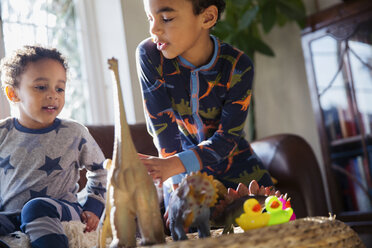 Brüder im Schlafanzug spielen mit Dinosaurier-Spielzeug - HOXF03908