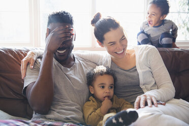 Lachende, glückliche multiethnische Familie auf dem Wohnzimmersofa - HOXF03927