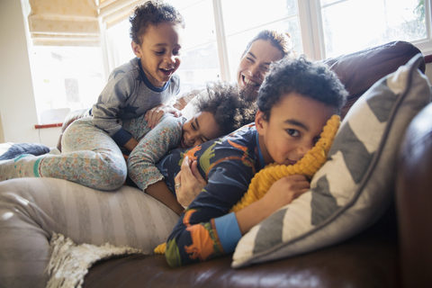 Portrait happy mother and children cuddling on living room sofa stock photo