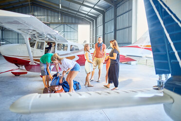 Freunde bereiten Taschen im Flugzeughangar vor - CAIF21747