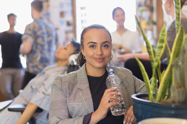 Porträt einer selbstbewussten Geschäftsfrau, die im Büro Wasser in Flaschen trinkt - CAIF21823