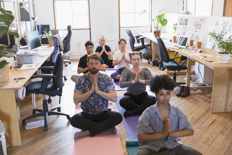 Kreative Geschäftsleute beim Meditieren im Büro, lizenzfreies Stockfoto