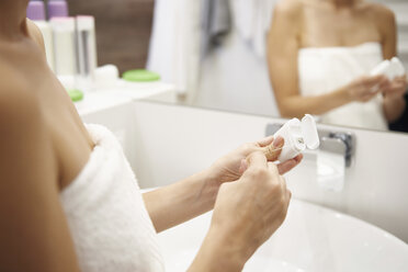 Woman using dental floss in bathroom, partial view - ABIF00988