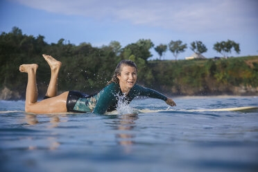 Indonesia, Bali, Balangan beach, female surfer lying on surfboard - KNTF01367