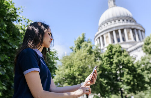 UK, London, junge Frau benutzt ihr Smartphone in der Nähe der St. Paul's Cathedral - MGOF03775