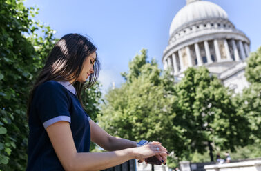 UK, London, junge Frau benutzt ihre Smartwatch in der Nähe der St. Paul's Cathedral - MGOF03776