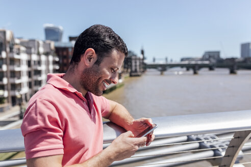 UK, London, Mann benutzt sein Smartphone auf der Millennium Bridge - MGOF03783