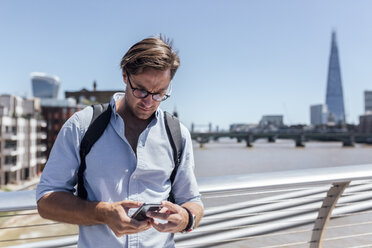 UK, London, man using his smartphone on the Millennium Bridge - MGOF03784