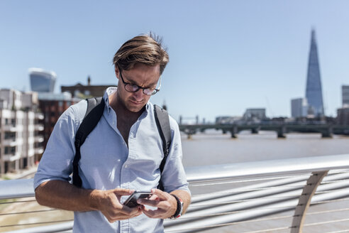 UK, London, Mann benutzt sein Smartphone auf der Millennium Bridge - MGOF03784