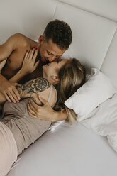 Happy young couple kissing in bed - LHPF00025