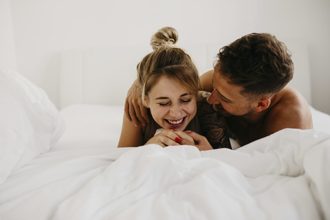 Romantisches glückliches junges Paar im Bett liegend, lizenzfreies Stockfoto