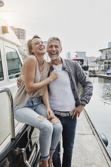 Lachender älterer Mann und junge Frau, die auf einem Steg neben einer Jacht stehen - RORF01553