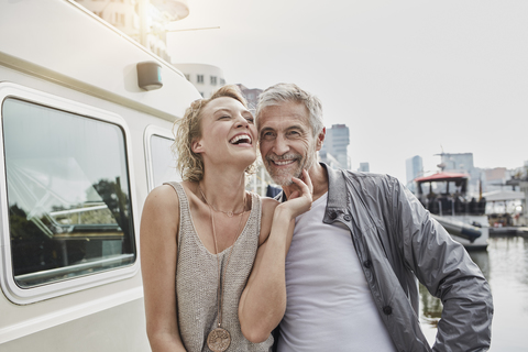 Glücklicher älterer Mann und junge Frau auf einem Steg neben einer Jacht, lizenzfreies Stockfoto