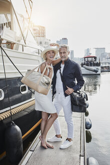 Älterer Mann und junge Frau stehen mit Reisetaschen auf dem Steg neben einer Jacht - RORF01555