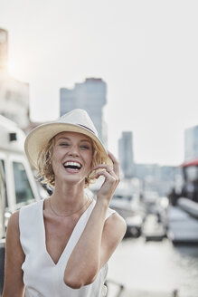 Porträt einer lachenden jungen Frau mit Hut in einem Jachthafen - RORF01559