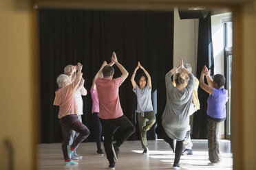 Aktive Senioren, die im Kreis trainieren und die Yoga-Baum-Pose üben - CAIF21877