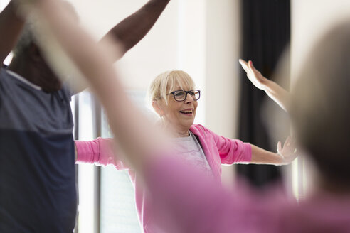 Lächelnde aktive ältere Frau, die ihre Arme im Sportunterricht ausstreckt - CAIF21883