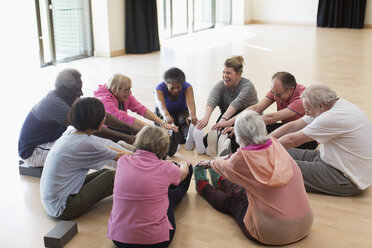 Active seniors exercising, stretching legs in circle - CAIF21892