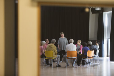 Eine Frau leitet eine Gruppendiskussion mit Senioren im Gemeindezentrum - CAIF21896