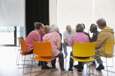 Active seniors talking in circle in community center - CAIF21909