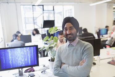 Portrait lächelnder, selbstbewusster indischer Computerprogrammierer mit Turban im Büro - CAIF21934