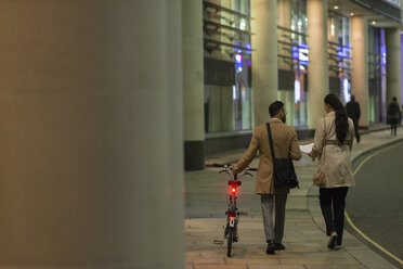 Geschäftsleute mit Fahrrad, die nachts auf dem Bürgersteig einer Stadt unterwegs sind - CAIF21965