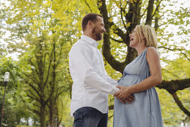 Happy mature pregnant couple talking in park - MFF04643