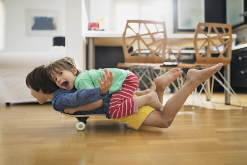 Zwei Brüder liegen zu Hause auf dem Skateboard und haben Spaß zusammen - AZOF00020