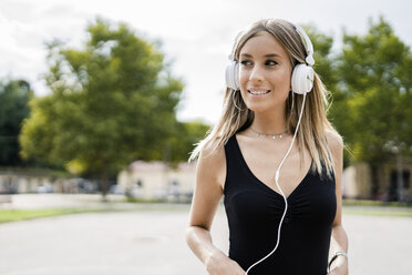 Portrait of smiling teenage girl wearing headphones - GIOF04361