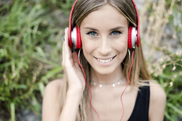Portrait of smiling teenage girl wearing headphones - GIOF04378