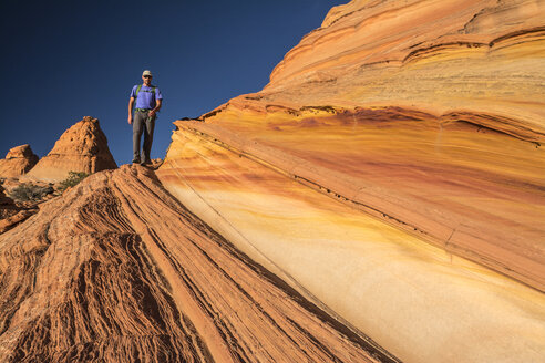 Ein Mann wandert entlang von Sandsteinschichten, Vermillion Cliffs National Monument, Kanab, Utah. - AURF04056